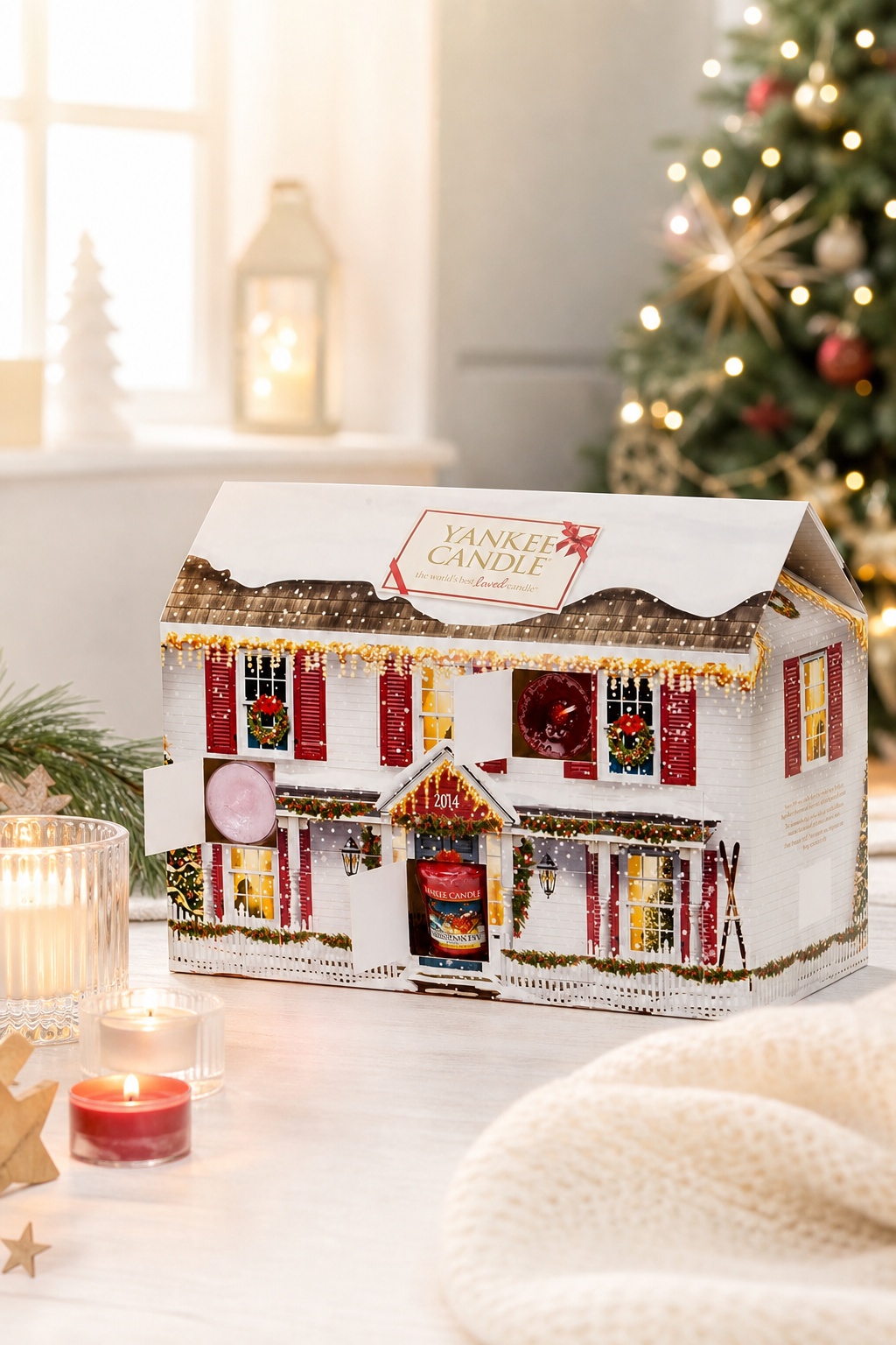 Yankee Candle Adventskalender Haus 2014 neben Weihnachtsbaum und brennenden Kerzen
