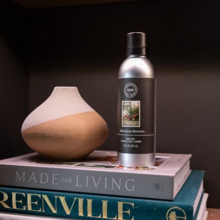 Afternoon Retreat Room Spray steht neben einer Vase auf gestapelten Büchern