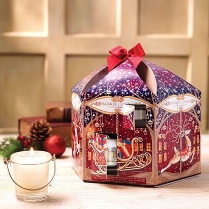 Yankee Candle Adventskalender mit geöffnetem Türchen neben brennender Kerze
