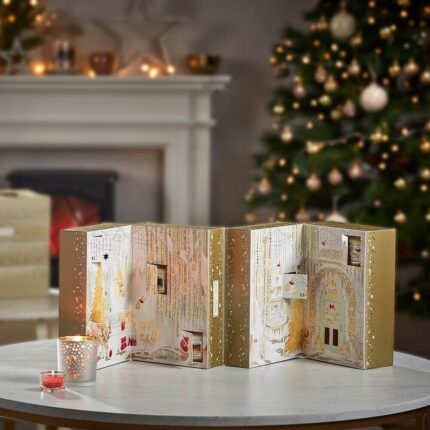 Geöffneter Yankee Candle Adventskalender mit nummerierten Fächern neben Weihnachtsbaum