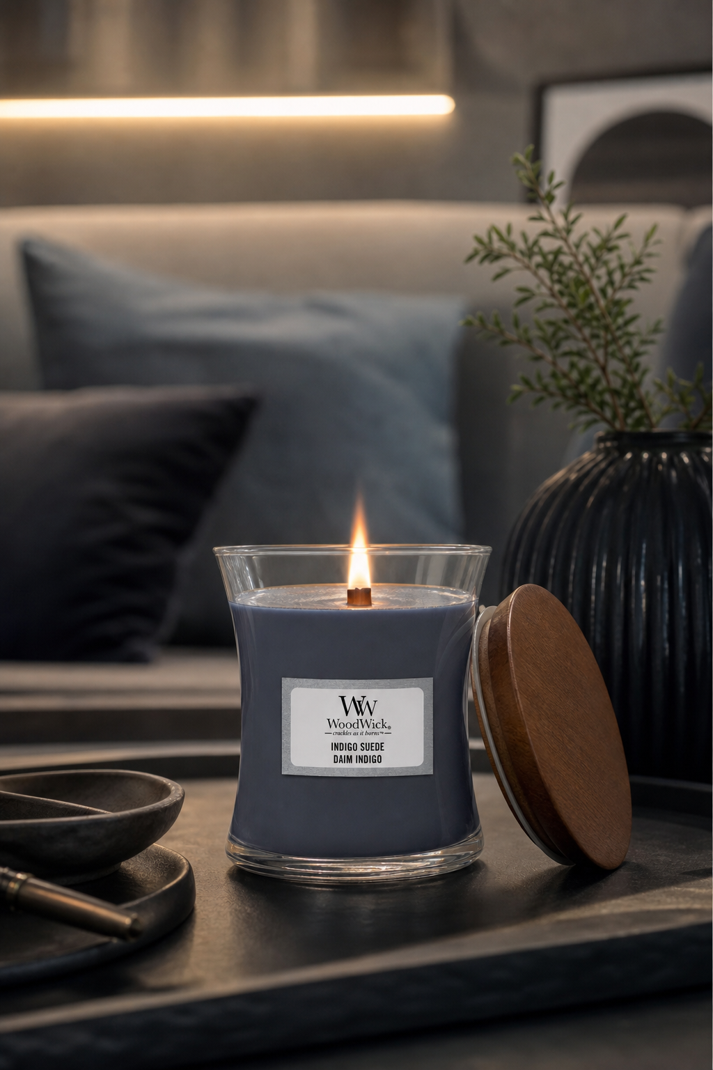 Brennende Indigo Suede Kerze im Glas neben abgenommenem Holzdeckel