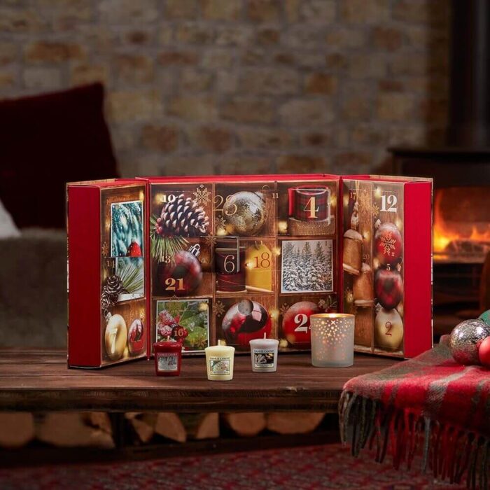 Geöffneter Adventskalender mit nummerierten Fächern und drei kleinen Kerzen