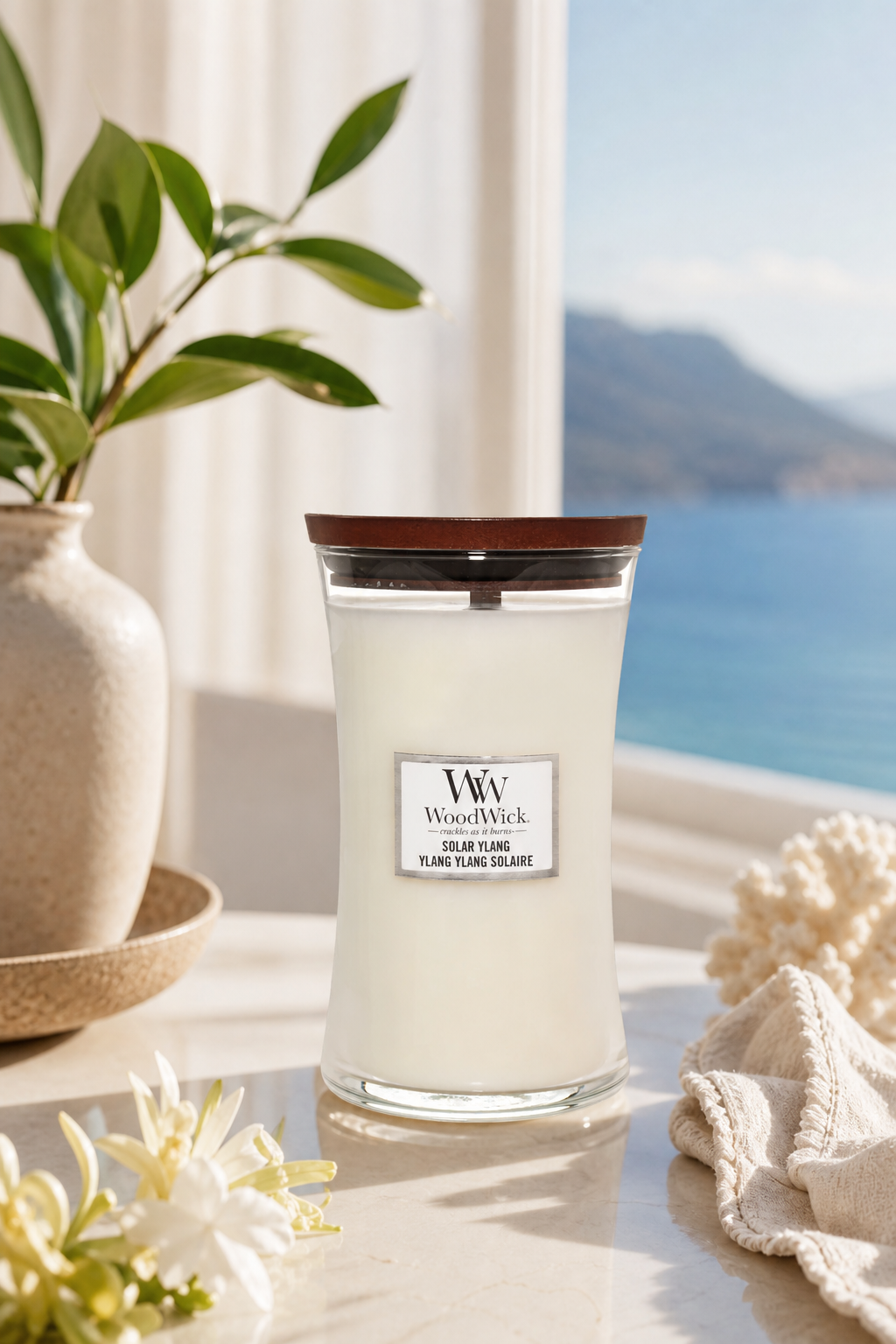Solar Ylang Kerze auf Tisch neben Pflanze und Fenster mit Seeblick