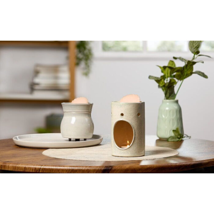 Zwei Duftlampen mit Wachsschalen auf einem gedeckten Holztisch