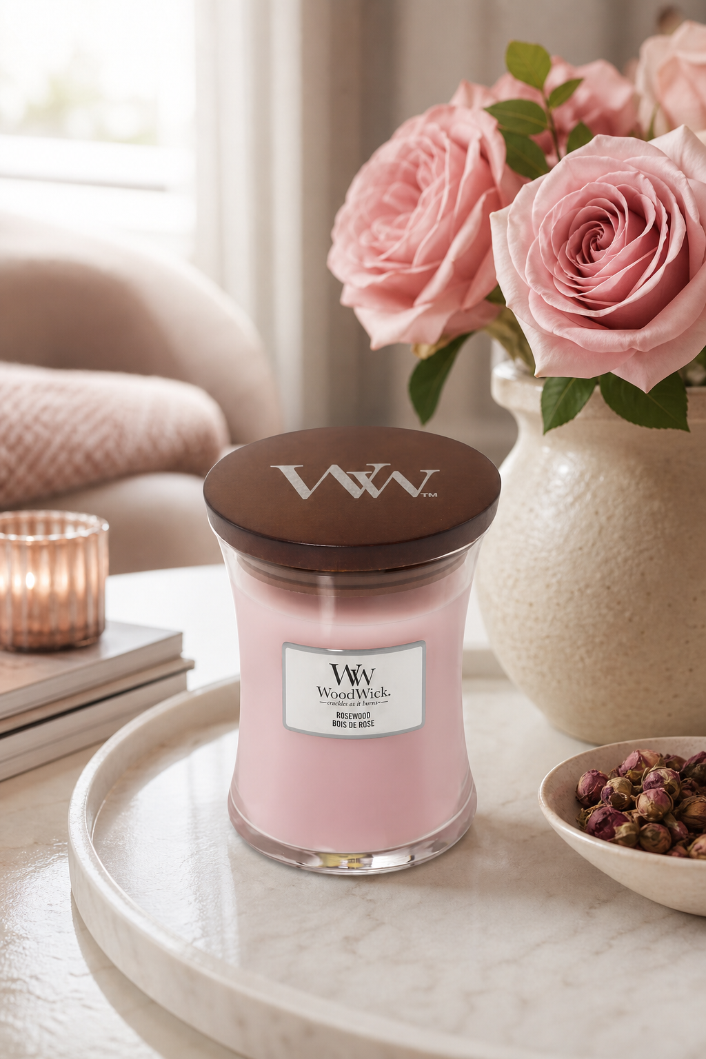 WoodWick Rosewood Kerze mit Deckel auf einem Tisch neben Rosen