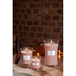 WoodWick Rosewood Kerze vor Blumen und Wohnzimmereinrichtung