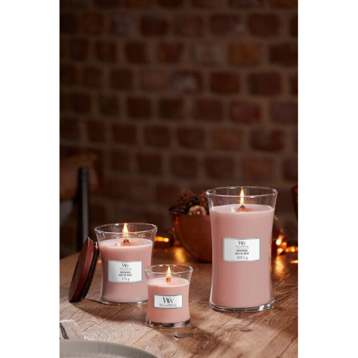 WoodWick Rosewood Kerze vor Blumen und Wohnzimmereinrichtung