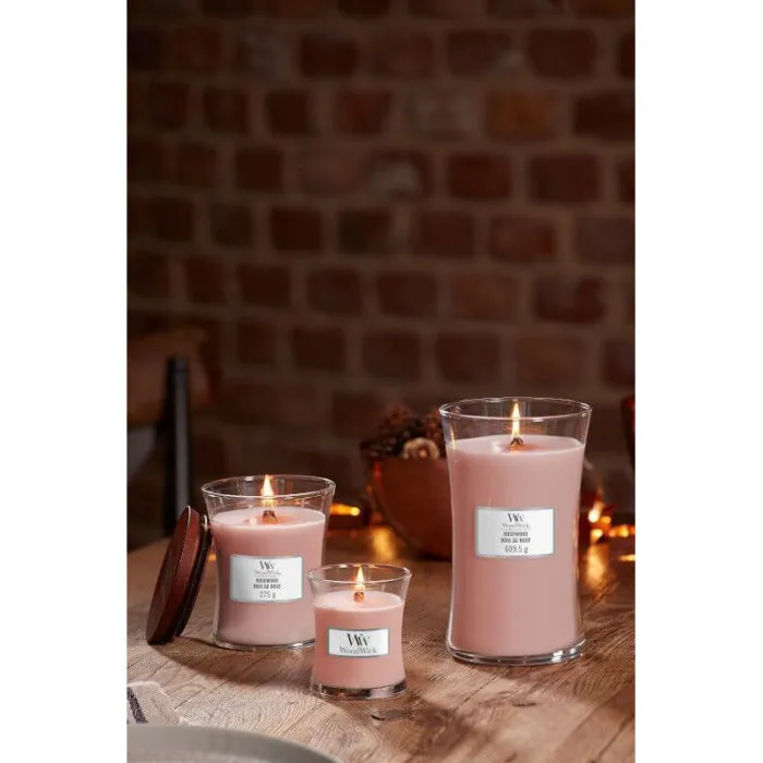 WoodWick Rosewood Kerze vor Blumen und Wohnzimmereinrichtung