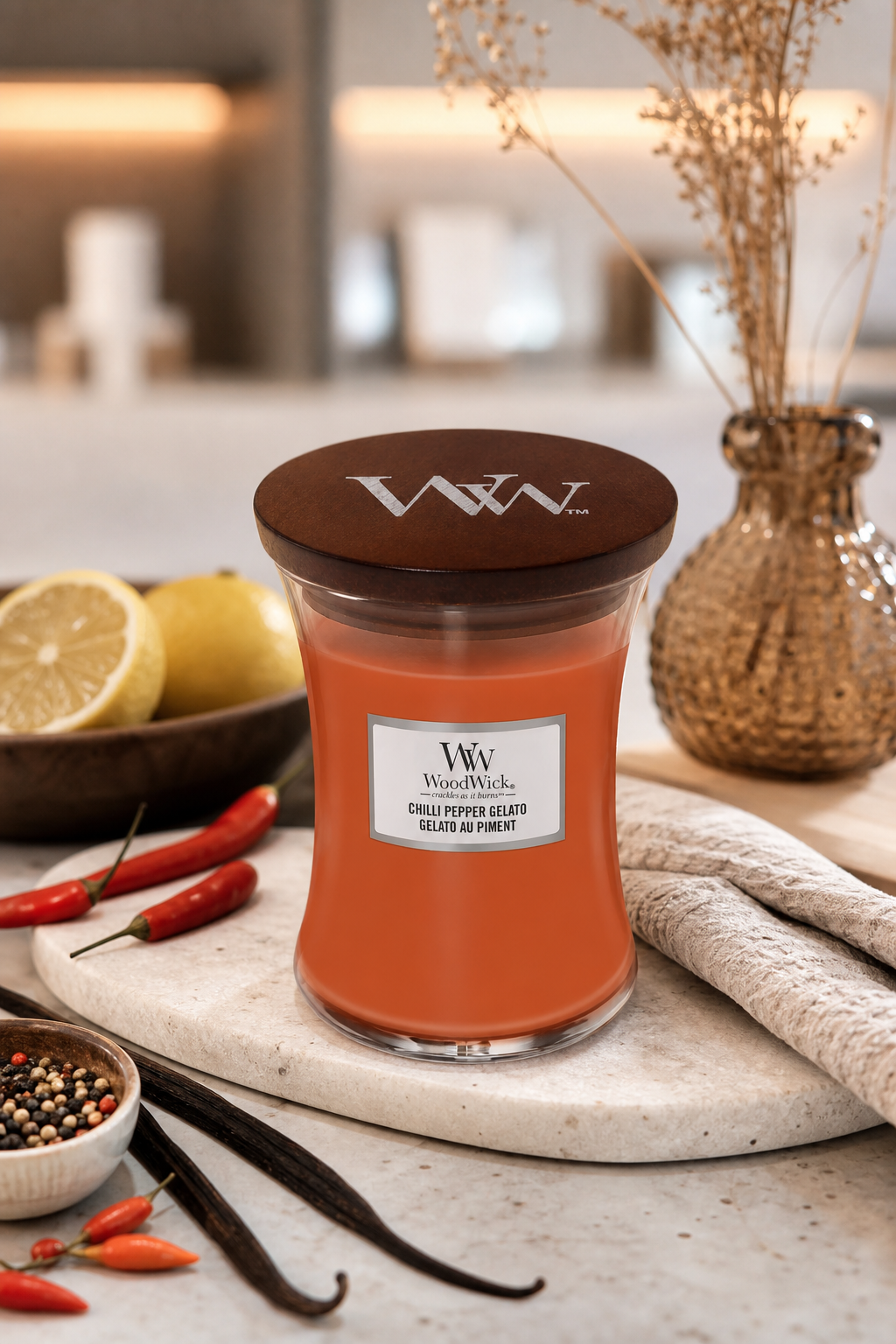 WoodWick Chilli Pepper Gelato Kerze auf Küchenarbeitsplatte mit Chilischoten und Zitronen