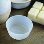 Weiße Schale steht auf einer Holzoberfläche neben Wachswürfeln