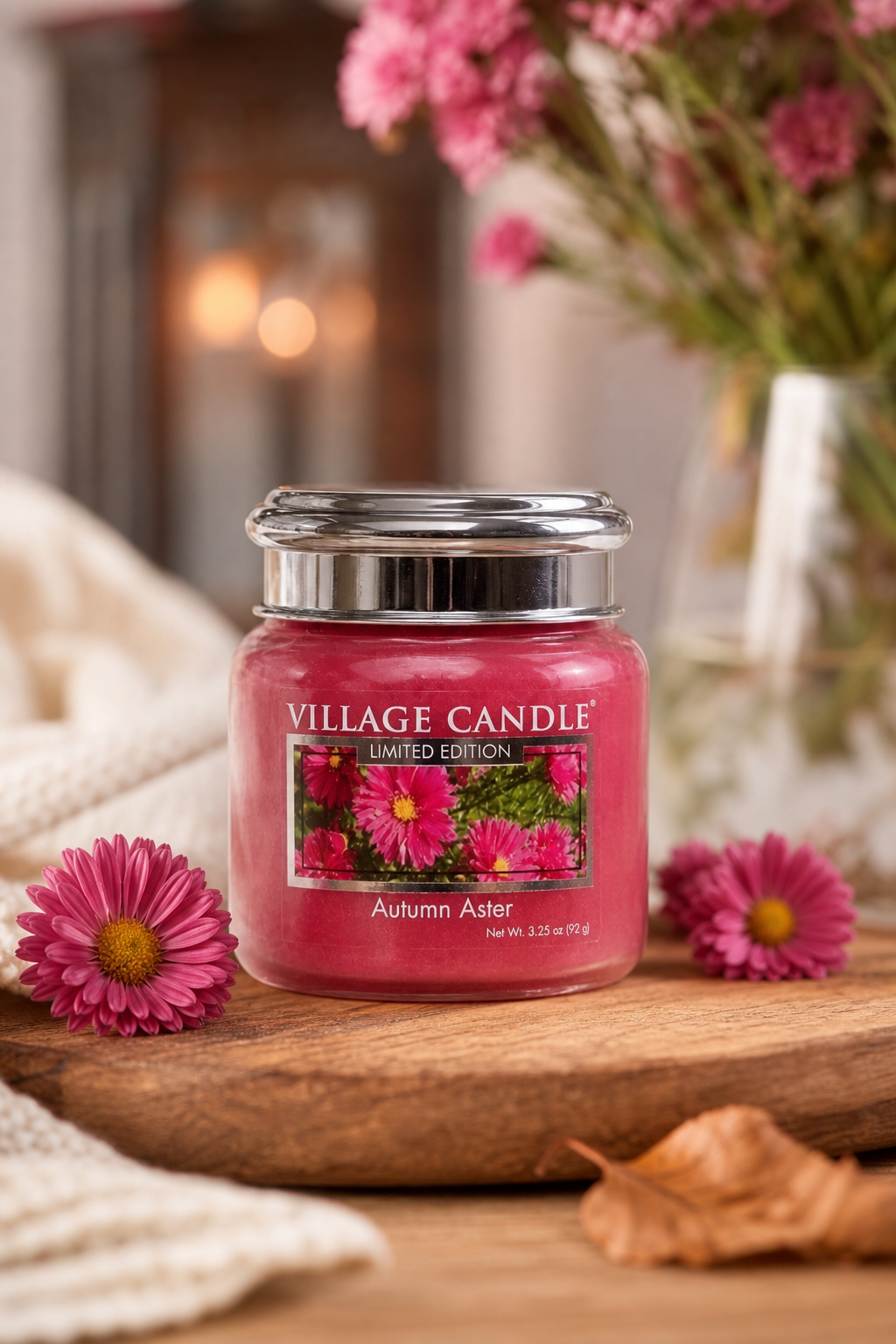 Rotes Village Candle Glas mit silbernem Deckel auf Holztisch neben Blumen