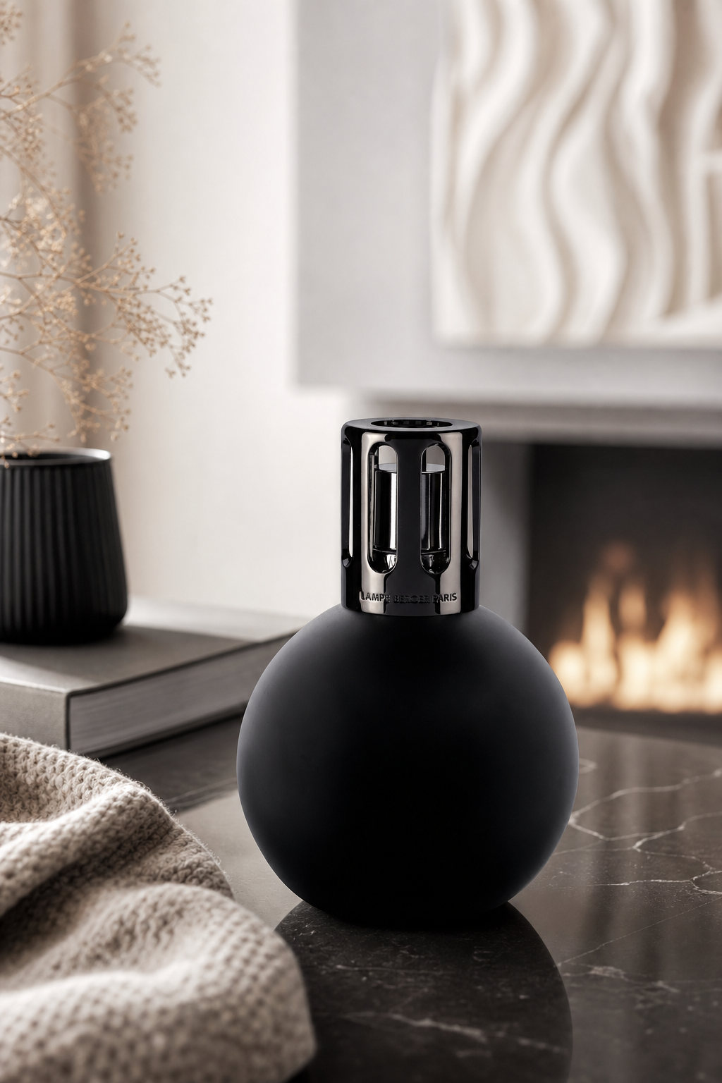 Schwarze runde Lampe Berger Boule auf einem Tisch neben einem Kamin