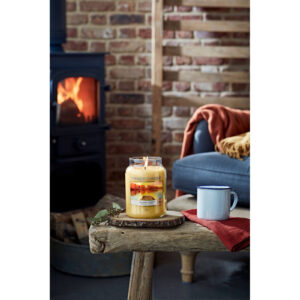 Brennende Yankee Candle Autumn Sunset Kerze auf einem Holztisch im Wohnzimmer