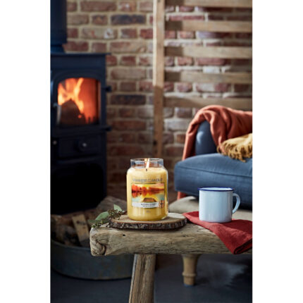 Brennende Yankee Candle Autumn Sunset Kerze auf einem Holztisch im Wohnzimmer
