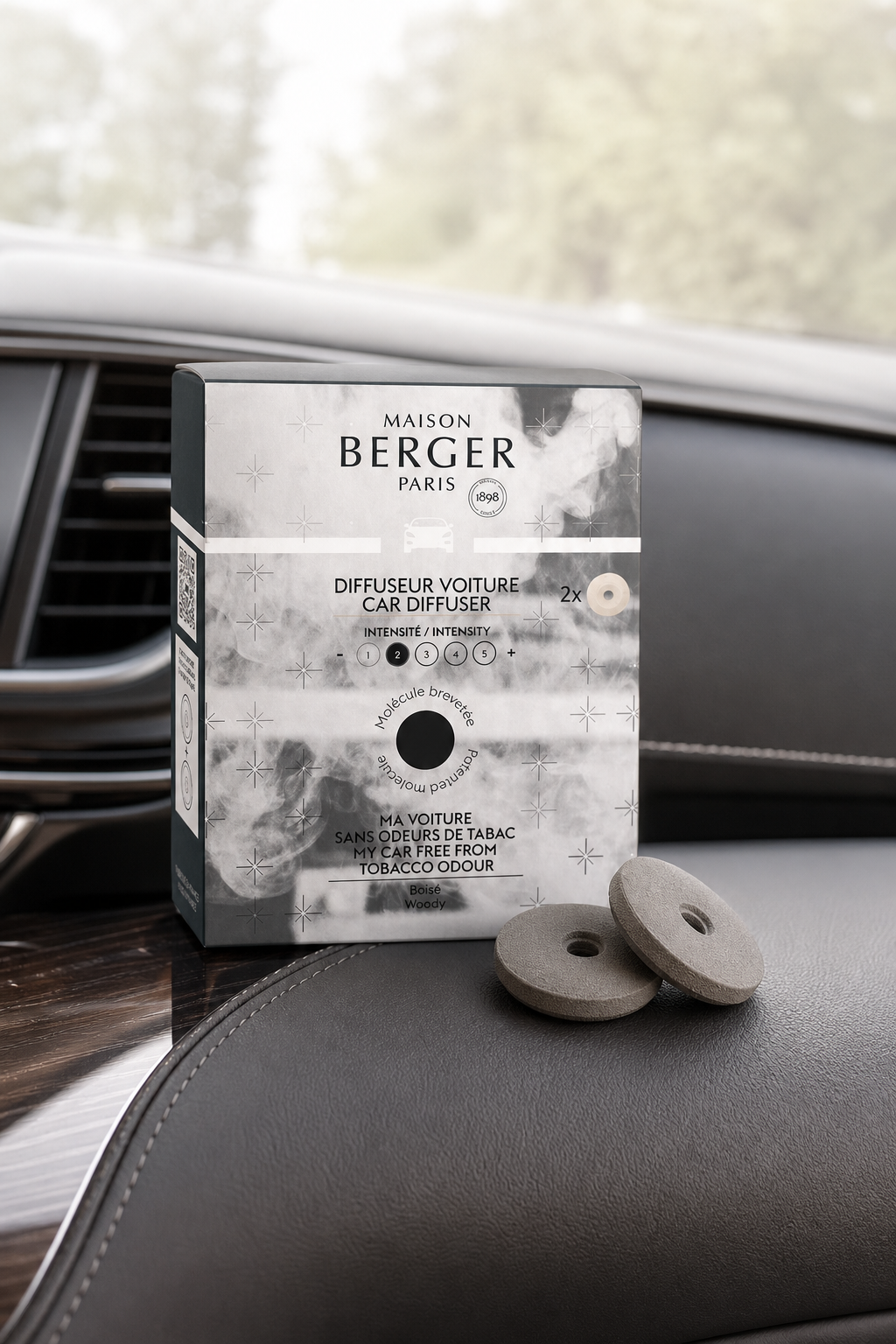 Maison Berger Paris Autoduft-Verpackung und zwei Nachfüllscheiben auf einer Fahrzeugkonsole
