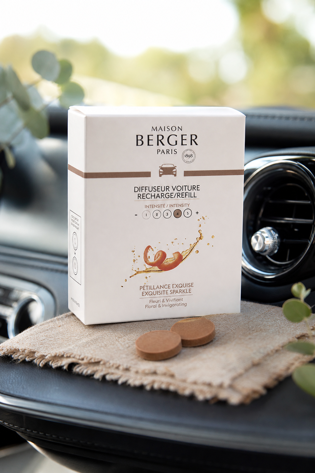 Maison Berger Paris Autoduft-Nachfüller-Verpackung liegt auf einem Tuch im Fahrzeuginnenraum