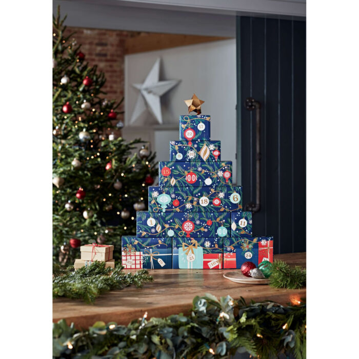 Adventskalender-Turm in weihnachtlich dekoriertem Wohnzimmer neben Kamin