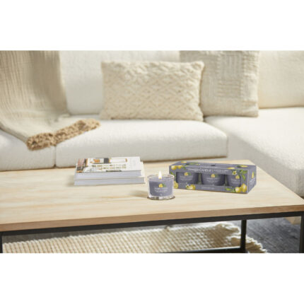Angezündete Yankee Candle Kerze und Black Tea & Lemon Dreierpack auf Tisch