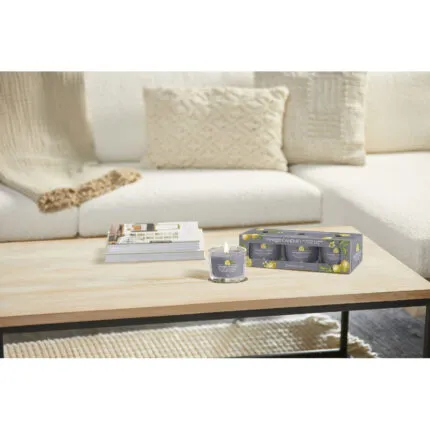 Angezündete Yankee Candle Kerze und Black Tea & Lemon Dreierpack auf Tisch