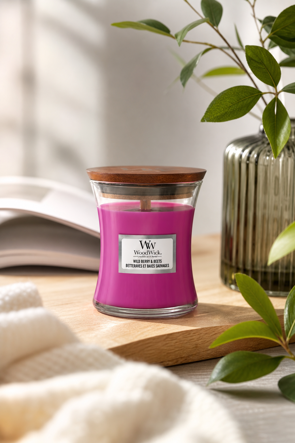 WoodWick Wild Berry & Beets Kerze mit Holzdeckel auf einem Holztisch