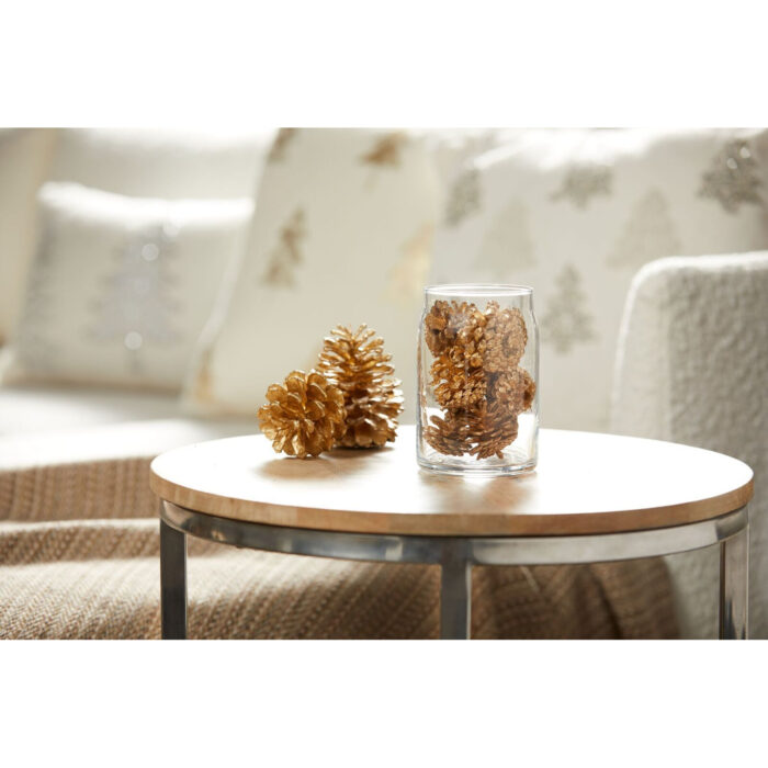 Glas mit goldenen Zapfen neben weiteren Zapfen auf einem Tisch