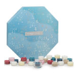 Yankee Candle Adventskalender neben Weihnachtsbaum und Teelichtkerzen