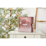 Geöffneter Adventskalender neben Weihnachtsdekoration auf einem Holztisch
