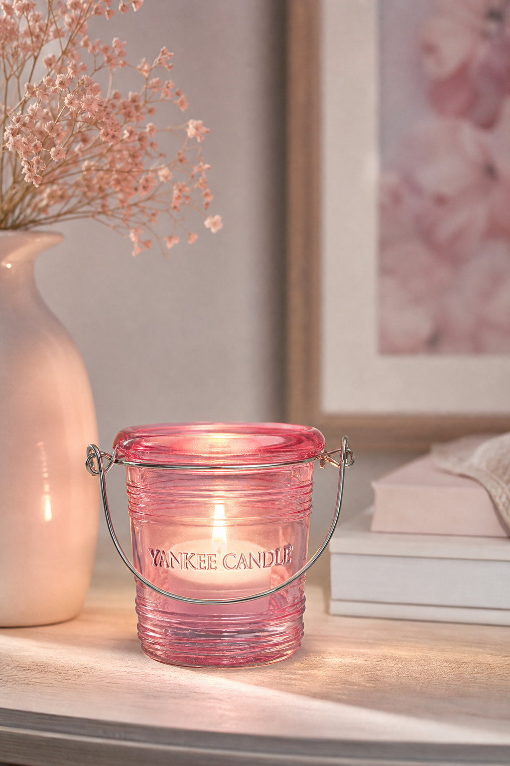 Rosa Yankee Candle Laternengefäß mit brennender Kerze auf einem Tisch