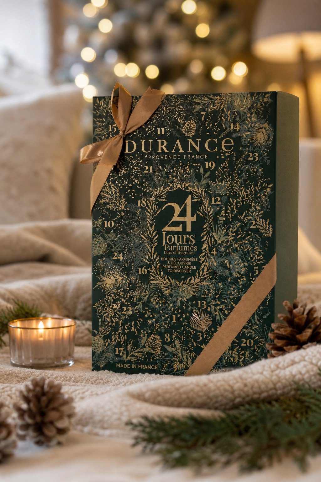 Durance Adventskalender mit Schleifenband neben Kerze und Tannenzweigen