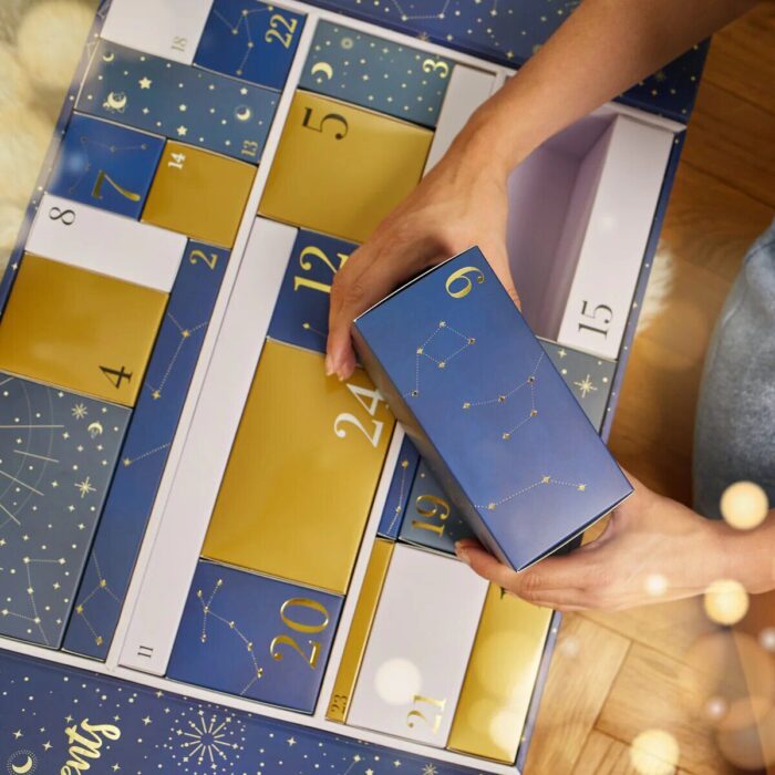 Hand öffnet eine nummerierte Schachtel im Magic Nights Adventskalender