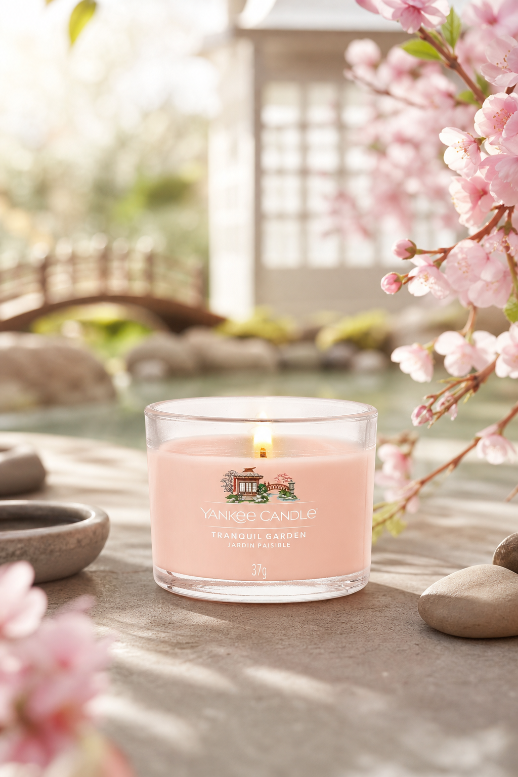 Brennende Yankee Candle Tranquil Garden im Glas vor einem Gartenmotiv