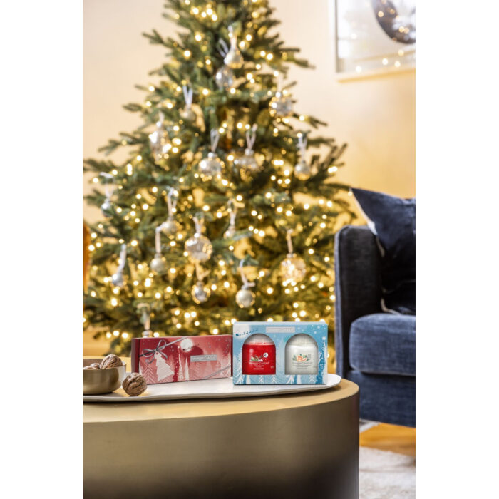 Zwei Yankee Candle Geschenkboxen stehen vor einem beleuchteten Weihnachtsbaum