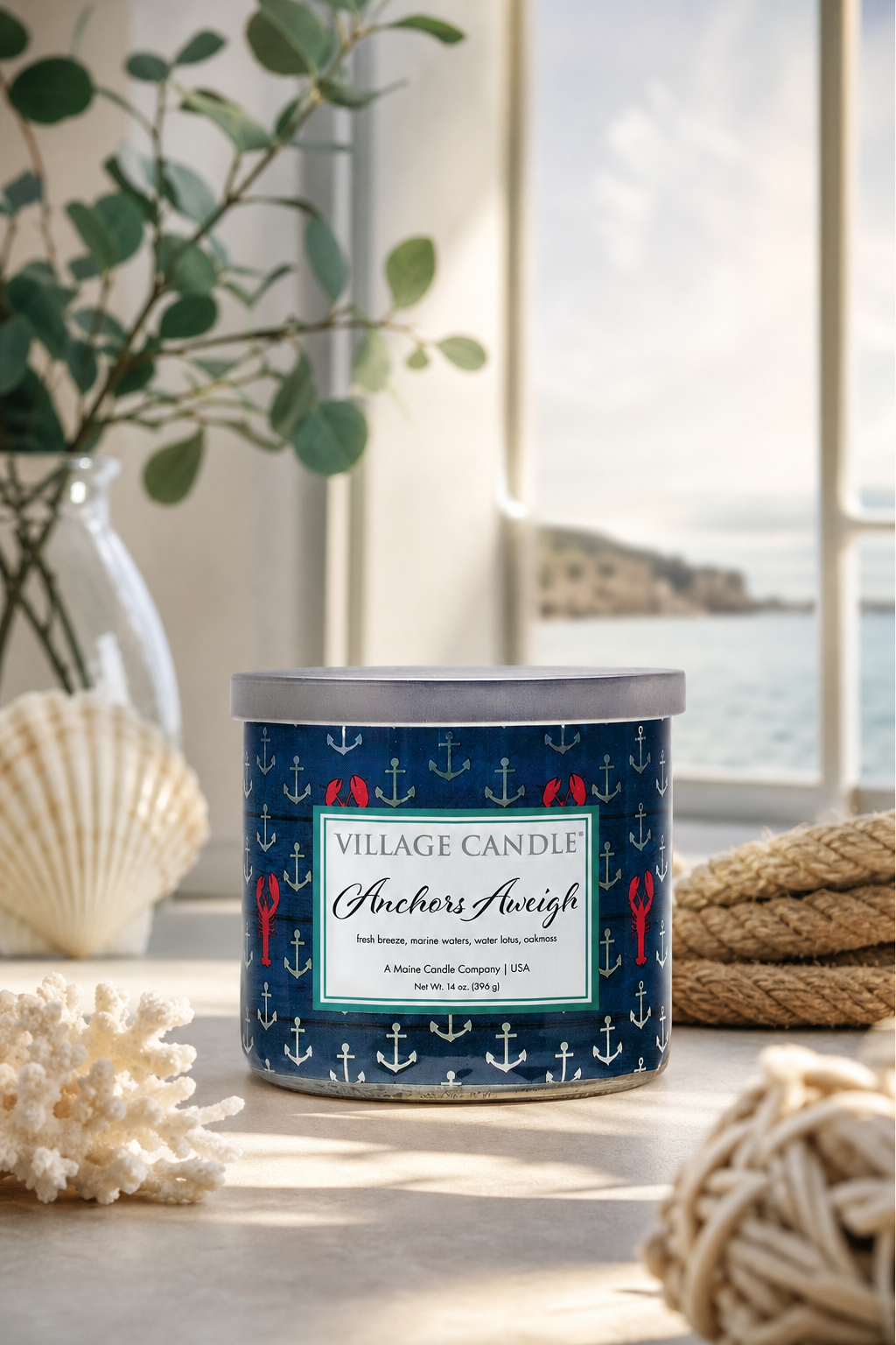 Anchors Aweigh Kerze von Village Candle auf Tisch vor einem Fenster mit Meerblick