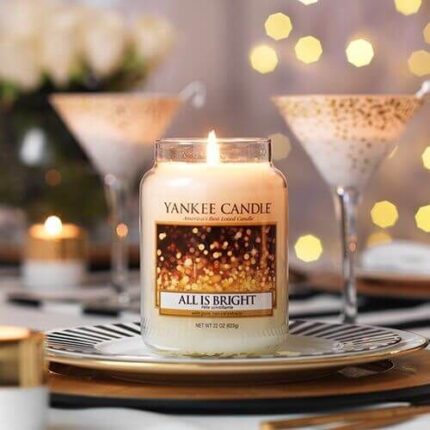 Brennende Yankee Candle All Is Bright Kerze auf einem gedeckten Tisch