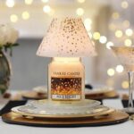 Yankee Candle All Is Bright Kerze mit aufgesetztem Lampenschirm auf einem Teller