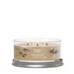 Brennende Yankee Candle Amber & Sandalwood Kerze auf rundem Kerzenhalter