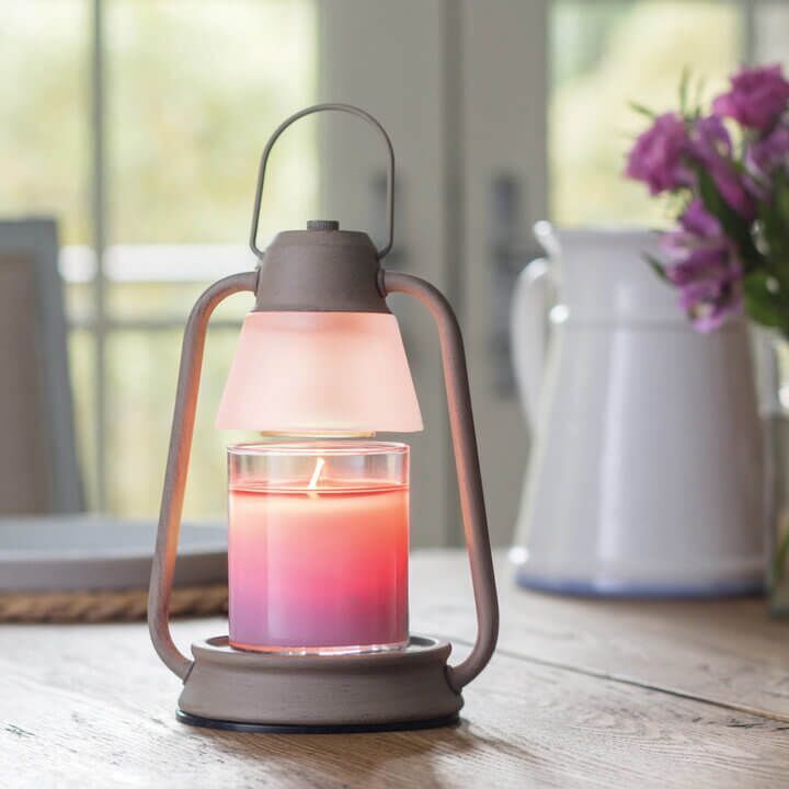 BEACON Laterne mit leuchtender Kerze vor Fenster und Blumen