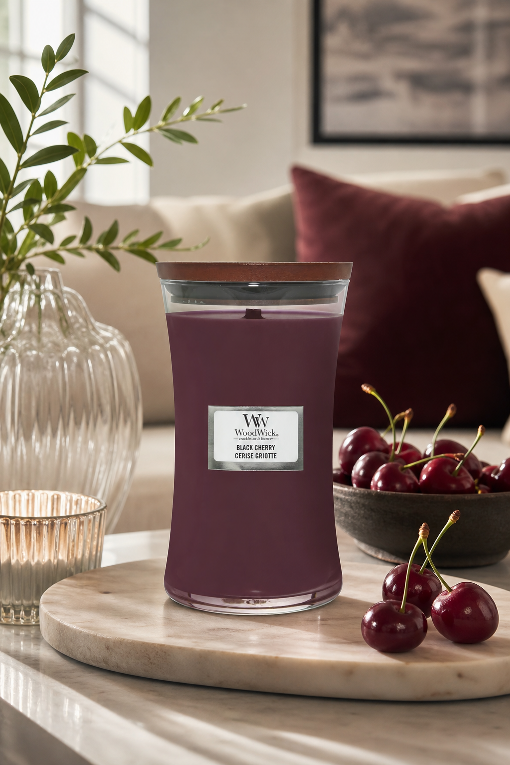 WoodWick Black Cherry Kerze auf Tisch neben Schale mit Kirschen
