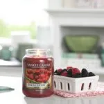 Brennende Black Cherry Kerze neben einer Schale mit Beeren