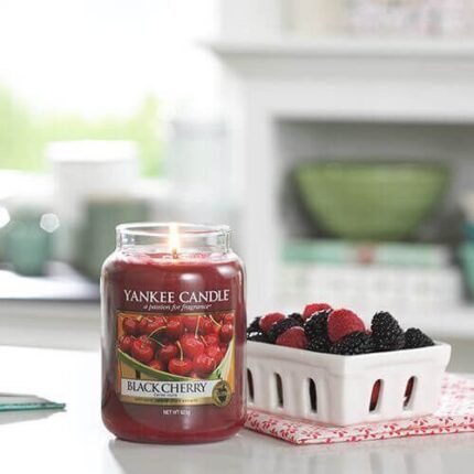 Brennende Black Cherry Kerze neben einer Schale mit Beeren