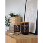 WoodWick Black Currant Rose Kerze neben kleiner brennender Kerze auf Ablage