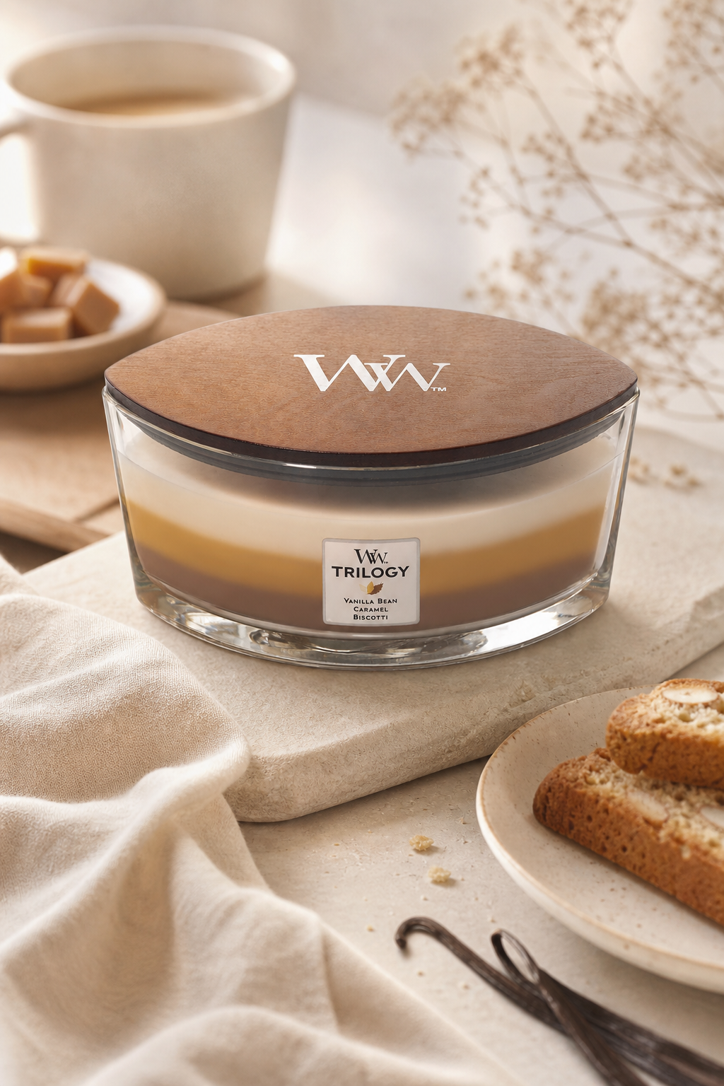 WoodWick Trilogy Kerze mit Holzdeckel neben Kaffee, Gebäck und Vanilleschoten
