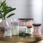 Mehrere WoodWick Kerzen mit brennender Trilogy-Kerze im Vordergrund