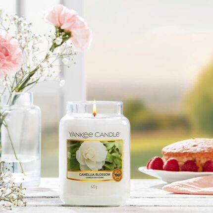 Brennende Yankee Candle Camellia Blossom Kerze auf gedecktem Tisch