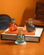 Mehrere Lampe-Berger-Modelle auf Büchern und runden Tischen