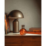 Orangefarbene Lampe Berger mit silberfarbenem Aufsatz auf einem Regal
