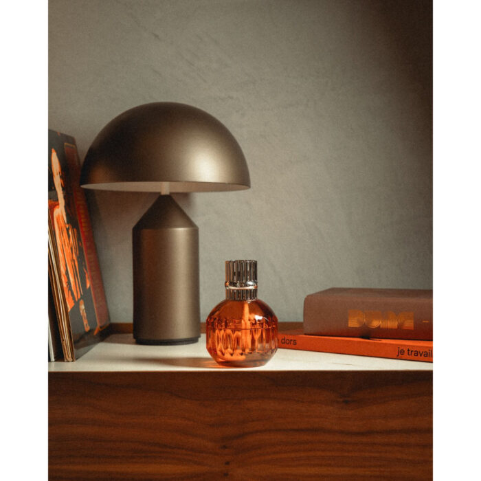 Orangefarbene Lampe Berger mit silberfarbenem Aufsatz auf einem Regal