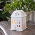 Hausförmige Duftlampe mit beleuchteten Fenstern auf einem Tisch