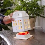 Hand hebt Hausaufsatz der Duftlampe über Duftwachsbehälter an