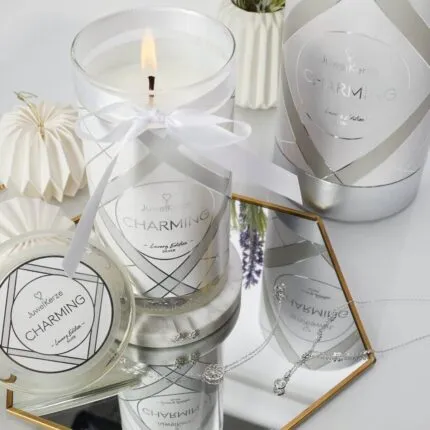 Brennende Charming Kerze neben Verpackung und Schmuck auf einem Tisch